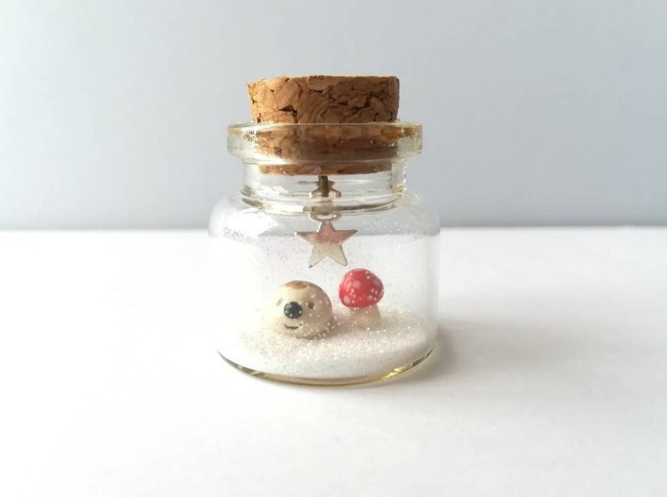 Miniature hedgehog and red toadstool Christmas decoration. Little pottery hedgehog in a glass bottle. Christmas woodland mini ornament