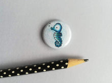 Load image into Gallery viewer, Mini seahorse button badge, the design is a little cute blue seahorse on a blue background
