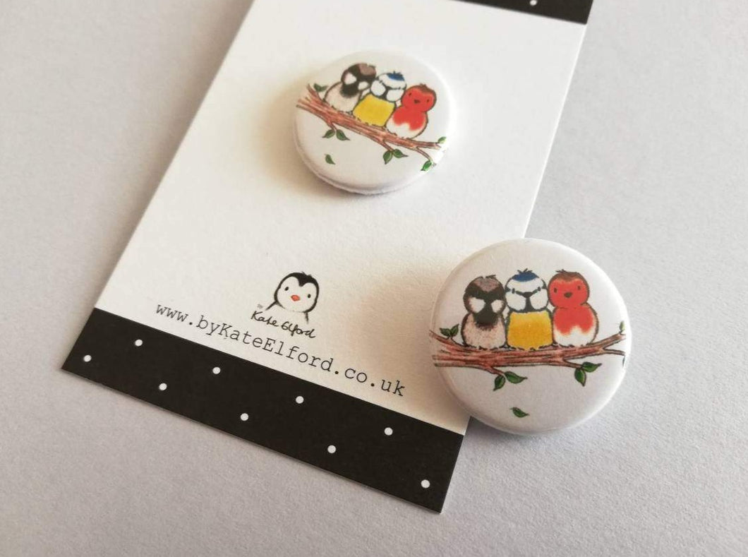 Mini round white button badge with an illustration of a sparrow, blue tit and robin sat on a branch