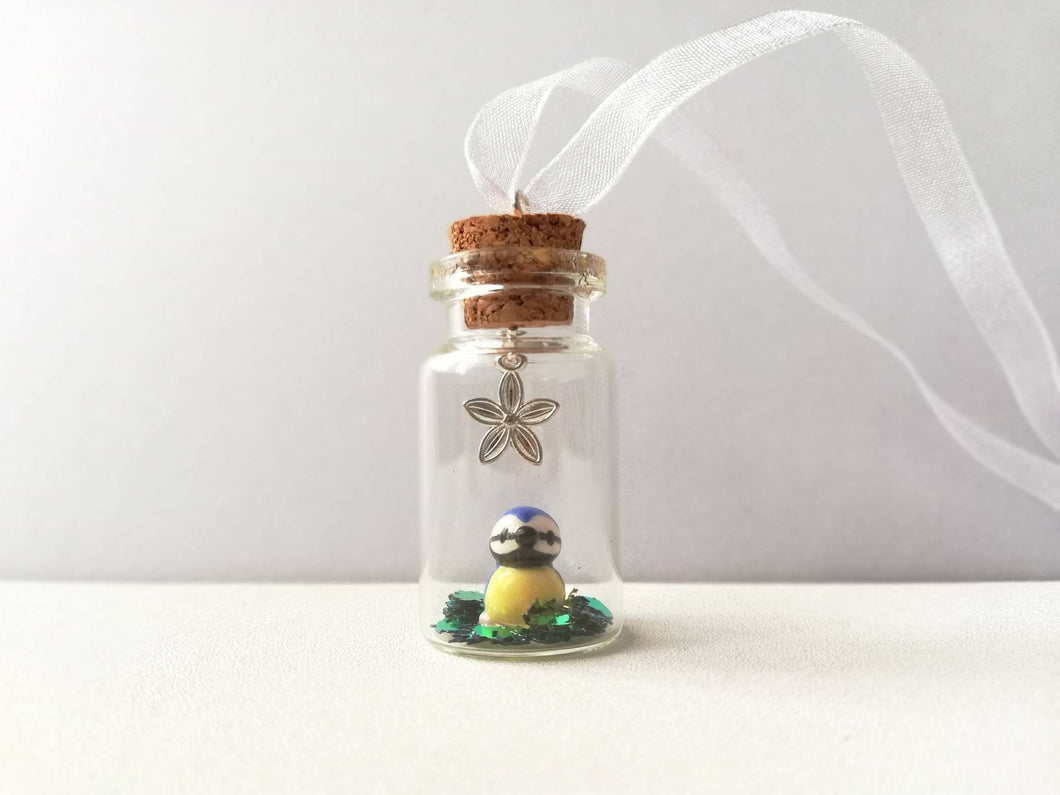 Miniature blue tit ornament. Little pottery bird in a glass bottle. Mini ornament and flower.