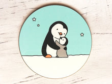 Load image into Gallery viewer, Penguin coaster. A black and white penguin and a grey penguin chick in the snow hugging. There is a light blue sky with a few stars
