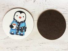 Load image into Gallery viewer, Penguin coaster. Penguin is wearing a polka dot blue dressing gown, slippers and having a cup of tea. Shows the back of the table mat
