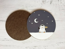 Load image into Gallery viewer, Round coaster. A little penguin dressed as a ghost. There are stars and the moon in the sky behind. Penguin is holding a flag that says Boo
