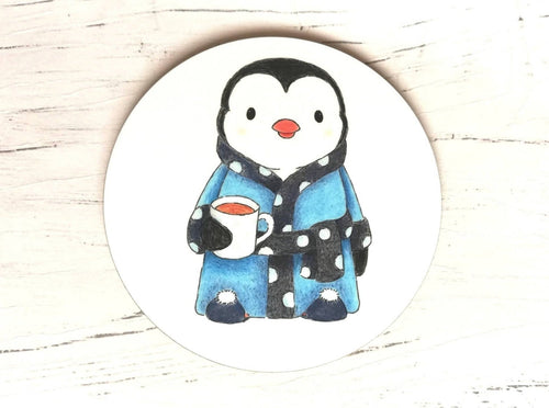 Penguin coaster. Penguin is wearing a polka dot blue dressing gown, slippers and having a cup of tea