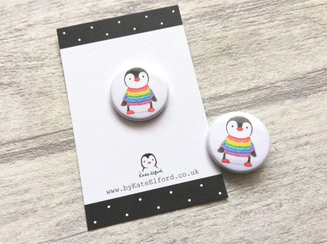 Mini button badge. A small round badge with a white background. The picture is a black and white penguin wearing a rainbow colour striped jumper