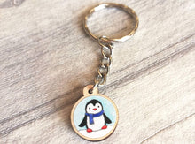 Load image into Gallery viewer, Little penguin keyring, cute mini tag, blue wooden key chain, penguin wearing a scarf in snow,ethically sourced wood, eco friendly charm
