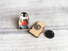 Load image into Gallery viewer, Penguin and pumpkin pin, grey penguin chick wooden pin brooch, Responsibly resourced wood, eco friendly. Halloween, autumn, fall badge
