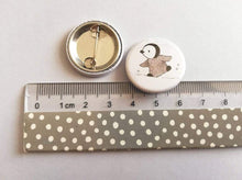 Load image into Gallery viewer, Grey penguin chick badge, front and back on a ruler to show the size
