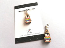 Load image into Gallery viewer, Small wooden stitch marker, little penguin design wearing a rainbow striped jumper
