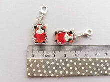 Load image into Gallery viewer, Guinea pigs in clear recycled acrylic wearing red jumper, hat and scarf. The charm has been turned into a stitch marker
