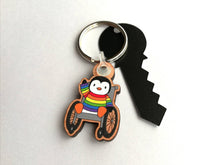 Load image into Gallery viewer, Penguin in a wheelchair keyring, rainbow penguin wooden key fob, penguin key chain, eco friendly charm, responsibly resourced wood
