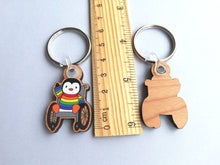 Load image into Gallery viewer, Penguin in a wheelchair keyring, rainbow penguin wooden key fob, penguin key chain, eco friendly charm, responsibly resourced wood
